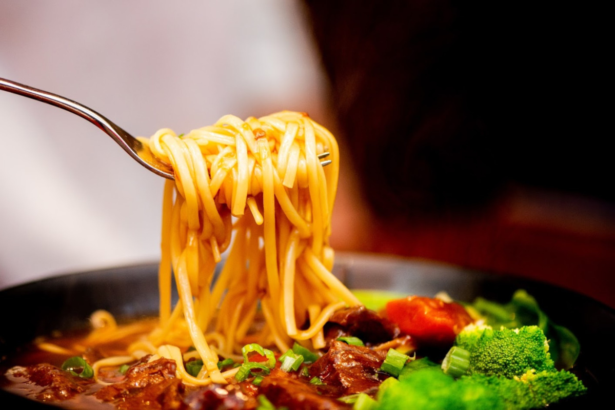 The Q signature dishes Spicy Szechuan Broth, All-You-Can-Eat Hot Pot, Hand-Pulled Noodles, Kobe Beef